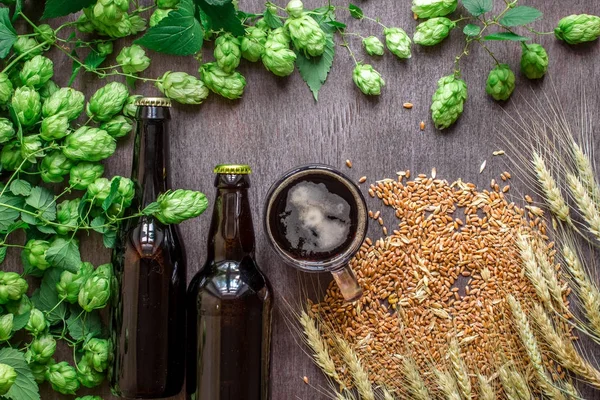Cerveza de botella y vidrio con trigo y lúpulo como ingredientes de elaboración de cerveza en la vista superior y área de espacio de copia — Foto de Stock