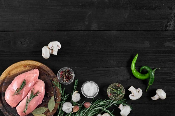 Çiğ tavuk göğsü fileto otlar, baharatlar, mantar ve biber ahşap kesme tahtası üzerinde. Kopya alanı ile Üstten Görünüm