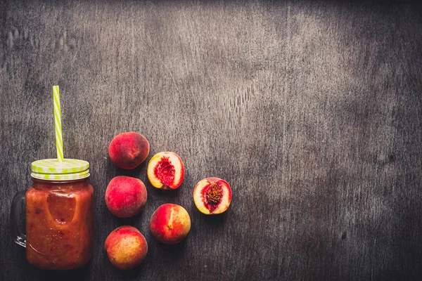 Batido de frutas de melocotón en botella de vidrio y pajitas en mesa de madera. Estilo de vida saludable. Tonificado — Foto de Stock