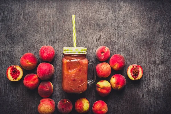 Batido de frutas de melocotón en botella de vidrio y pajitas en mesa de madera. Estilo de vida saludable. Tonificado — Foto de Stock