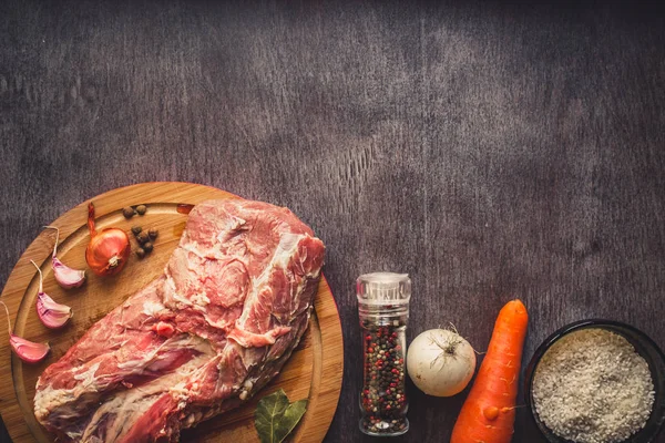 Çiğ domuz eti koyu ahşap yüzey ve yemek pişirmek için malzemeler. Gıda arka plan kopya alanı ile. Tonda