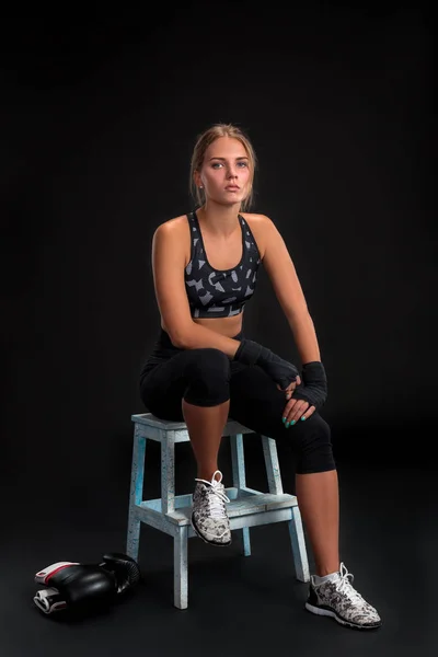 Mujer joven en forma mirando a la cámara mientras envuelve sus brazos con cinta adhesiva. Chica atractiva preparándose para el entrenamiento de kickboxing . —  Fotos de Stock