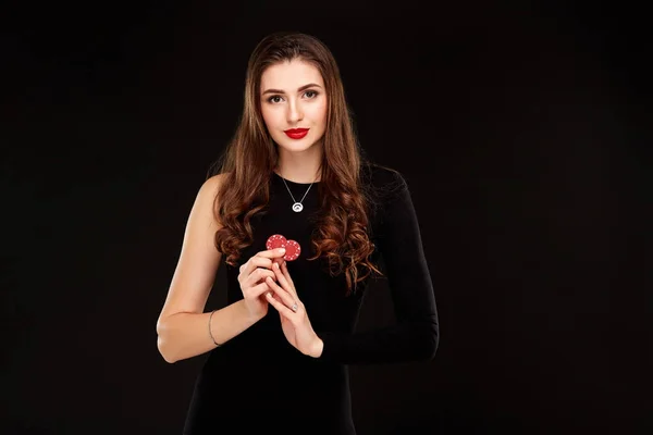Sexy lockiges Haar brünett posiert mit Chips in den Händen, Poker-Konzept schwarzen Hintergrund — Stockfoto