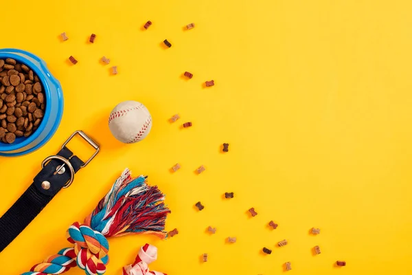 Brinquedos multi-colorido corda, bola e alimentos secos. Acessórios para jogar no fundo amarelo vista superior — Fotografia de Stock