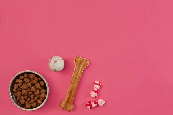 Snacks para cães, mastigas para cães, ossos para cães, brinquedos de bola para cães em um fundo rosa com espaço de cópia — Fotografia de Stock