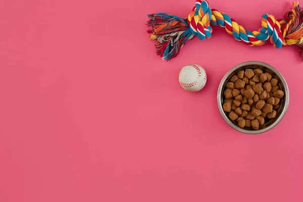 Brinquedos multi-colorido corda, bola e alimentos secos. Acessórios para jogar no fundo rosa vista superior — Fotografia de Stock