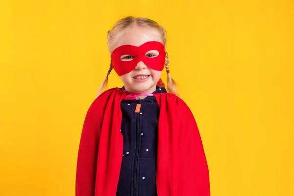 Забавна маленька силова супергеройська дівчинка в червоному плащі та масці. концепція супергероя . — стокове фото