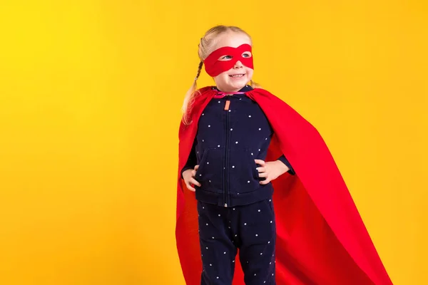 Забавна маленька силова супергеройська дівчинка в червоному плащі та масці. концепція супергероя . — стокове фото