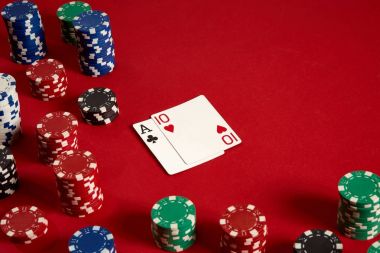 Poker kartları ve kırmızı zemin üzerine kumar fişleri