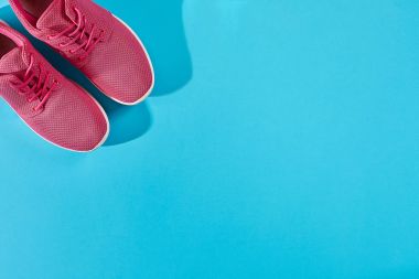 Kopya alanı ile mavi arka plan üzerinde yeni pembe spor ayakkabı. Spor kavramı