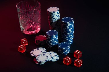 Poker fişleri ve konyak karanlık masada Şarap kadehi. Kumar