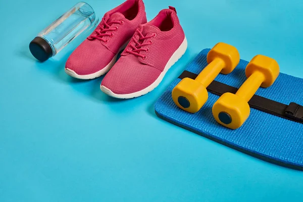 Healthy concept, diet plan with sport shoes and bottle of water and dumbbells on blue background, healthy food and exercise concept