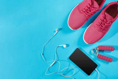 Düz Spor donatımı atış yatıyordu. Spor ayakkabı, kulaklık, telefon mavi zemin üzerine.