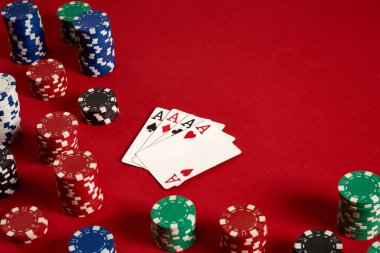 Poker kartları ve kırmızı zemin üzerine kumar fişleri