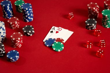 Poker kartları ve kırmızı zemin üzerine kumar fişleri