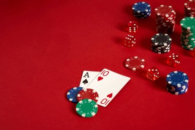 Poker kartları ve kırmızı zemin üzerine kumar fişleri