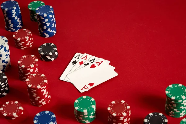 Poker kartları ve kırmızı zemin üzerine kumar fişleri