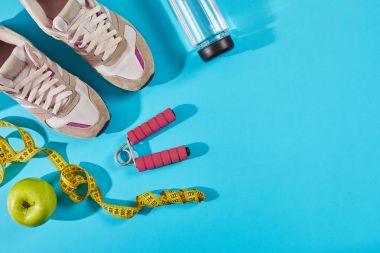 Teyp siyan mavi zemin üzerine ölçme ile spor ayakkabıları. Santimetre yakınında beyaz eğitimciler, sarı renkte yakın çekim.