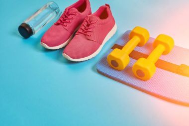 Sağlıklı kavramı, spor ayakkabı ve bir şişe su ve dumbell ile diyet planı mavi arka plan, sağlıklı yiyecek ve egzersiz kavramı. Güneş parlaması