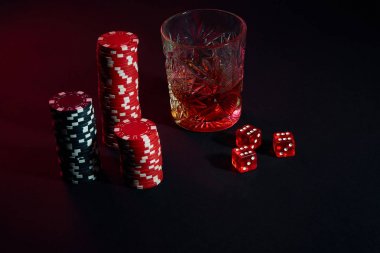 Poker fişleri ve konyak karanlık masada Şarap kadehi. Kumar