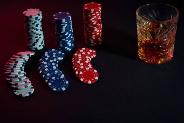 Poker fişleri ve konyak karanlık masada Şarap kadehi. Kumar