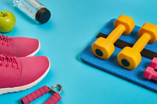Healthy concept, diet plan with sport shoes and bottle of water and dumbbells on blue background, healthy food and exercise concept