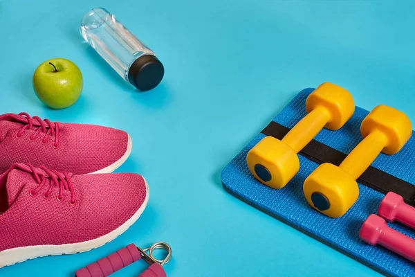 Healthy concept, diet plan with sport shoes and bottle of water and dumbbells on blue background, healthy food and exercise concept