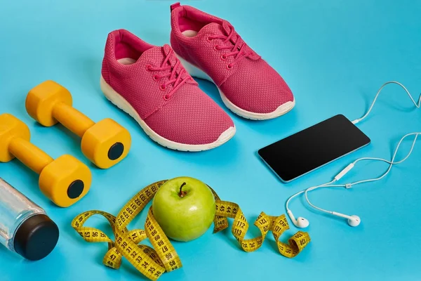 Conceito saudável, plano de dieta com sapatos esportivos e garrafa de água e halteres em fundo azul, comida saudável e conceito de exercício — Fotografia de Stock