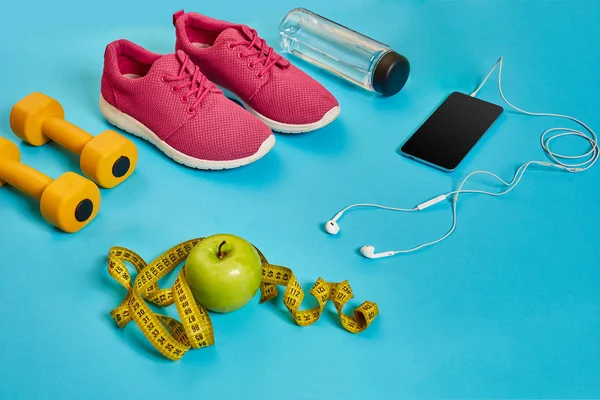 Conceito saudável, plano de dieta com sapatos esportivos e garrafa de água e halteres em fundo azul, comida saudável e conceito de exercício — Fotografia de Stock