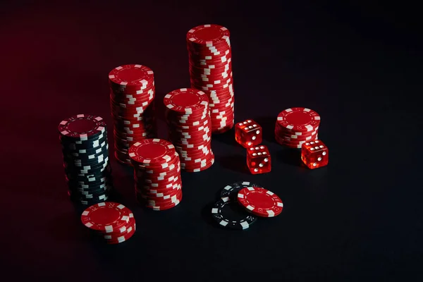Dice and red and black chips on dark background — Stock Photo, Image