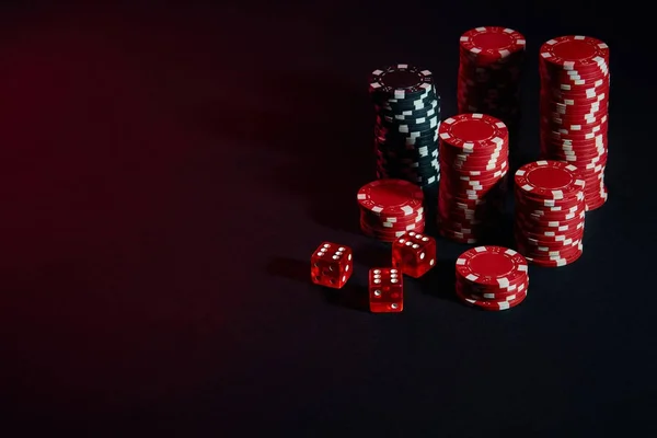 Dice and red and black chips on dark background — Stock Photo, Image