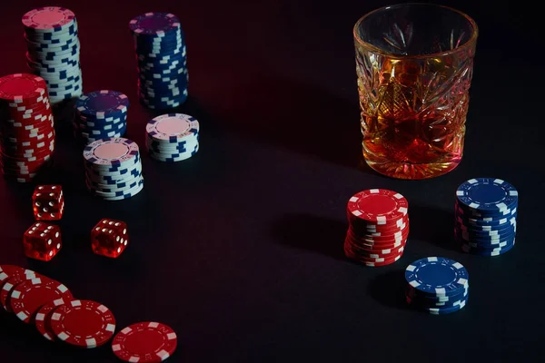Fichas de póquer y copa de vino de coñac en la mesa oscura. Juegos de azar — Foto de Stock