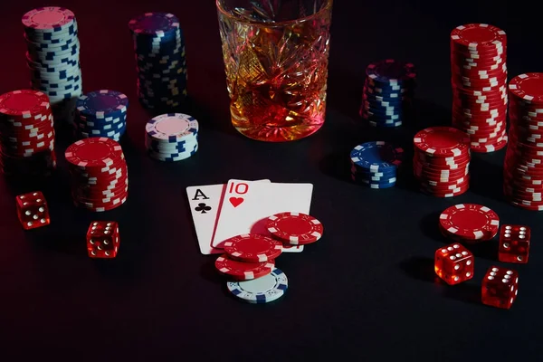 Cards of poker player. On the table are chips and a glass of cocktail with whiskey. Combination of cards