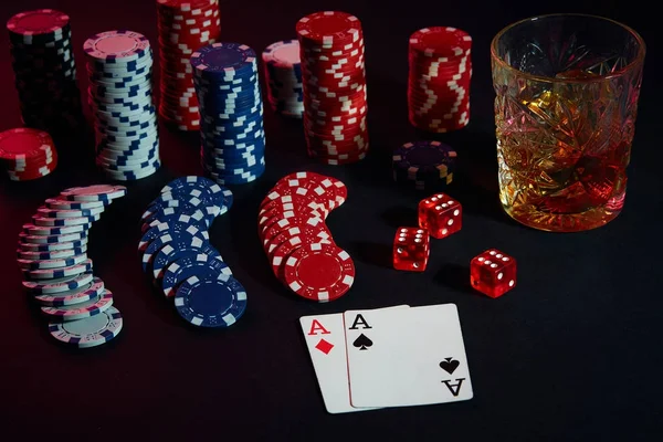 Cards of poker player. On the table are chips and a glass of cocktail with whiskey. Combination of cards
