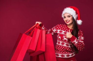 Genç kadın ya da Noel Baba şapkası güzel uzun saçlı kız güzel ve kırmızı studio arka plan üzerinde kırmızı paket holding yeni yıl elbise