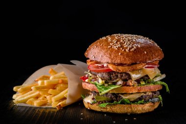 Peynirli hamburger ızgara et, peynir, domates ve patates koyu ahşap yüzey üzerinde. Reklam için idealdir. Yakın çekim