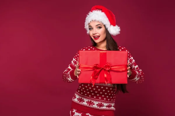 Młody piękną kobietę Boże Narodzenie obecny w jej ręce na tle czerwony studio — Zdjęcie stockowe
