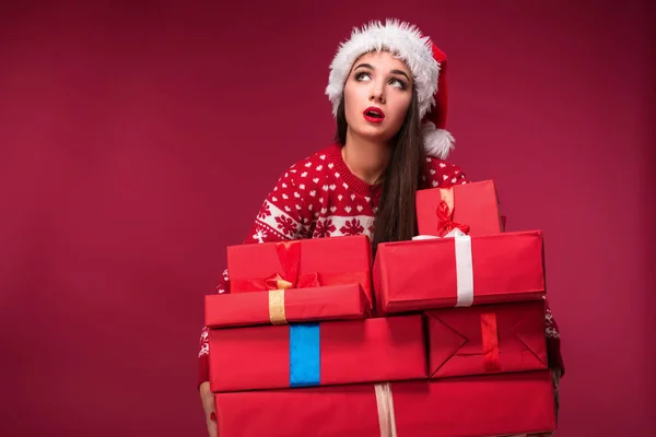 Młoda kobieta w sweter i Boże Narodzenie kapelusz gospodarstwa pudełeczka na czerwonym tle — Zdjęcie stockowe