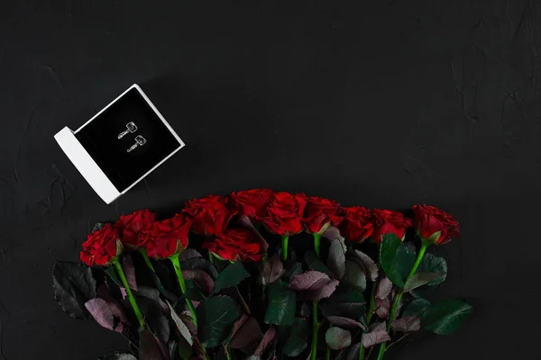 Un ramo de rosas rojas y una caja con pendientes. Vista superior — Foto de Stock