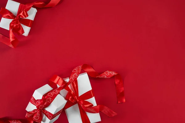 Witte geschenkdozen met rood lint op rode achtergrond. Valentines d — Stockfoto