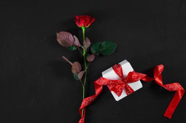 Bir koyu kırmızı siyah backgrou kırmızı kurdele ve hediye kutusu ile yükseldi
