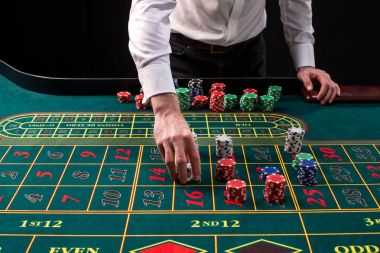 Yeşil casino rulet, krupiye ve çok renkli fiş elleriyle tabloyla bir yakın çekim canlı görüntüsünü.