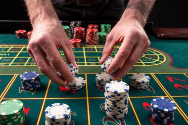 Yeşil casino rulet, krupiye ve çok renkli fiş elleriyle tabloyla bir yakın çekim canlı görüntüsünü.