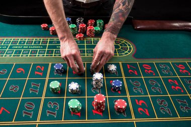 Yeşil casino rulet, krupiye ve çok renkli fiş elleriyle tabloyla bir yakın çekim canlı görüntüsünü.