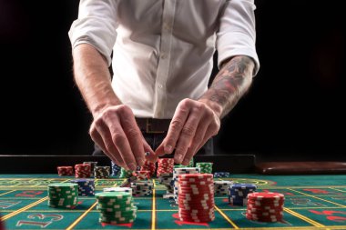 Yeşil casino rulet, krupiye ve çok renkli fiş elleriyle tabloyla bir yakın çekim canlı görüntüsünü.