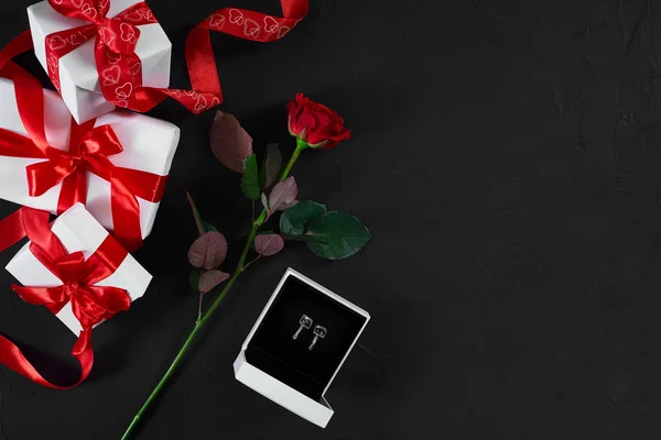 En mörk röd ros och box med örhängen på svart bakgrund. Rom — Stockfoto