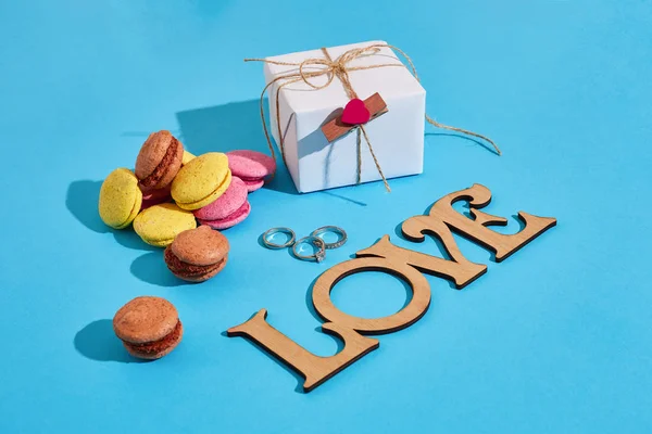 Macaroons e caixa de presente em um fundo azul com as palavras que eu amo — Fotografia de Stock