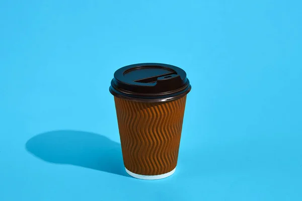 Ζεστό καφέ στο καφέ χαρτί Κύπελλο με μαύρο καπάκι σε μπλε φόντο — Φωτογραφία Αρχείου