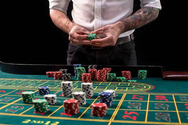 Ein lebendiges Bild von grünem Casino-Tisch mit Roulette, mit den Händen von Croupier und bunten Chips. — Stockfoto