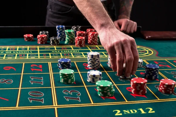 Une image animée en gros plan de table de casino verte avec roulette, avec les mains de croupier et de jetons multicolores . — Photo